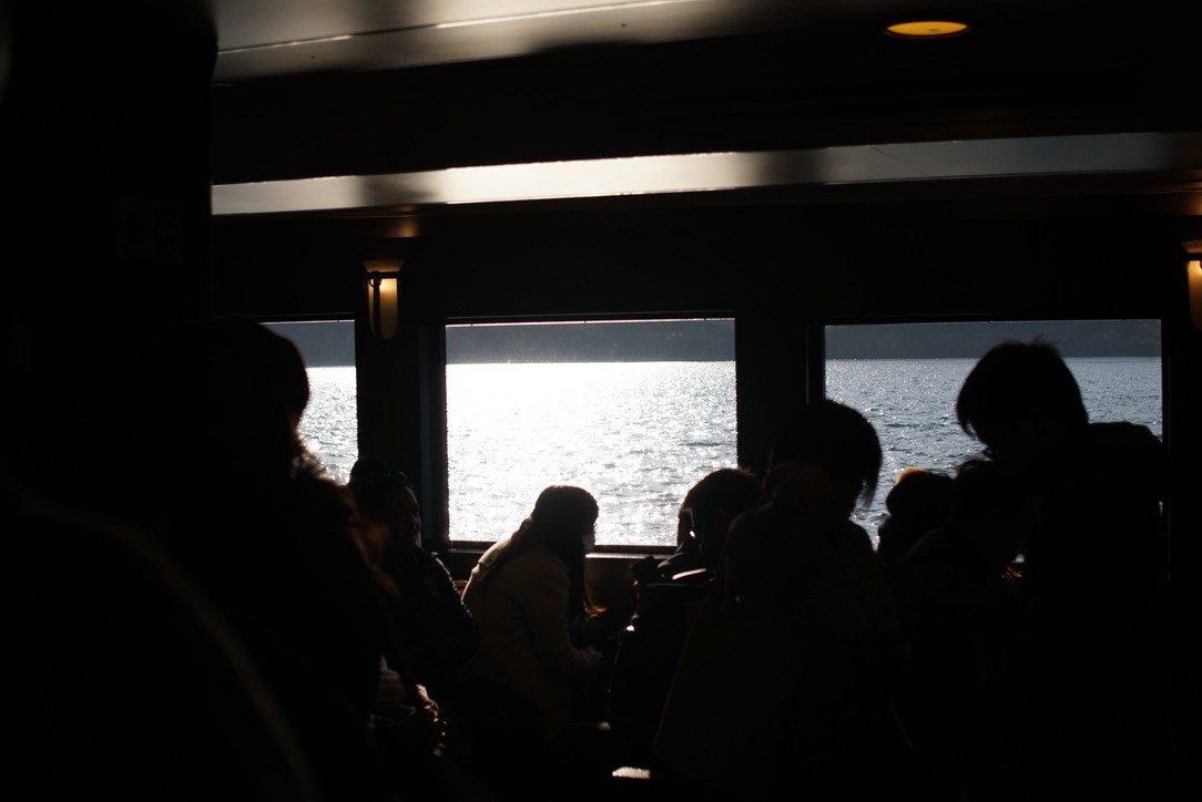 Passengers silhouetted against the sea through ferry windows