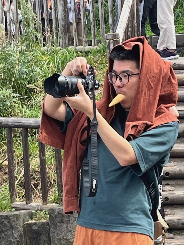 Zack holding a camera with an ice cream cone in his mouth