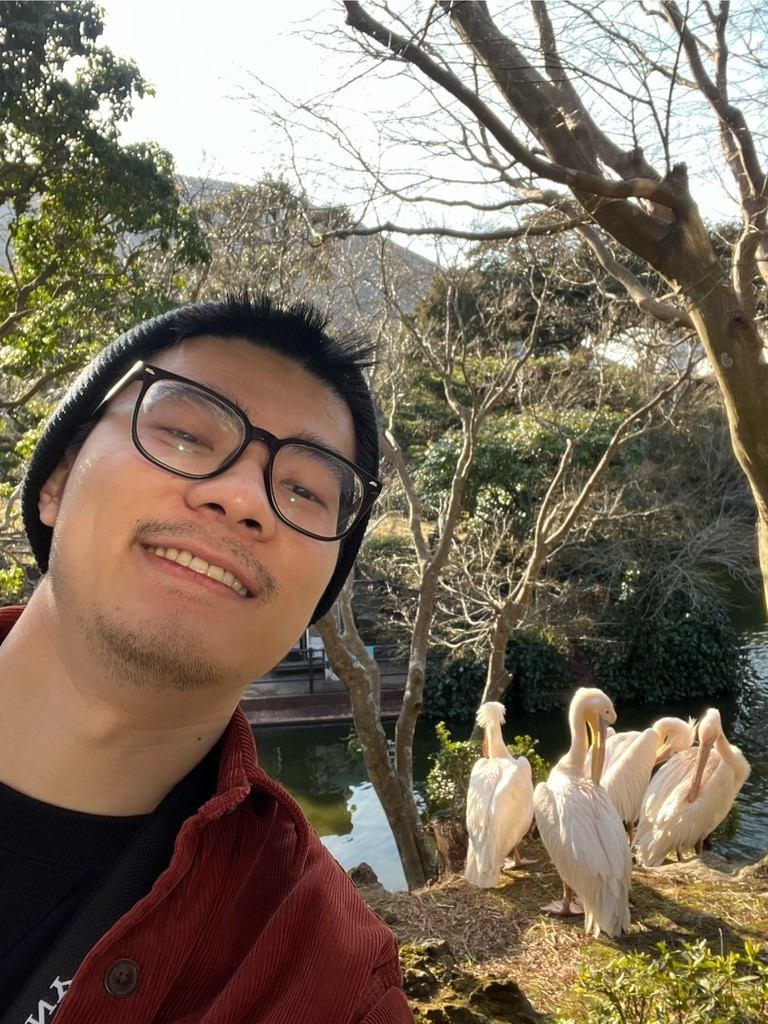 Zack taking a selfie beside a group of pelicans